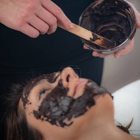 Eine schöne Frau bereichert ihre Hautpflege mit einer üppigen Schönheitsmaske aus Schokolade