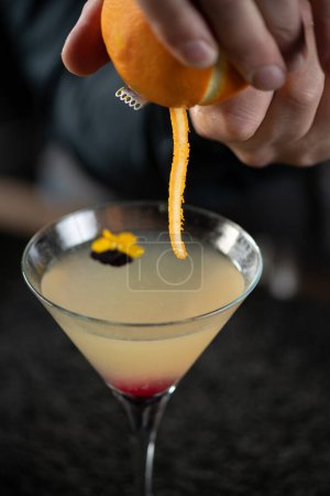 Photo for Bartender delicately piling fresh orange, adding citrus pill to a crafted Ginger Apple Vermouth Cocktail. - Royalty Free Image