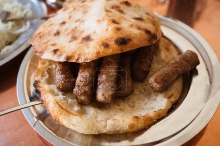 Téléchargez les photos : Cevapi bosniaque le plat national de Bosnie-Herzégovine à base de boeuf haché et d'agneau et je servi avec des oignons, ajvar et pain somun - en image libre de droit