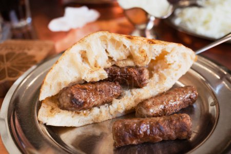 Bosnian Cevapi  the National Dish of Bosnia and Herzegovina made with minced beef and lamb and i served with onions, ajvar and somun bread