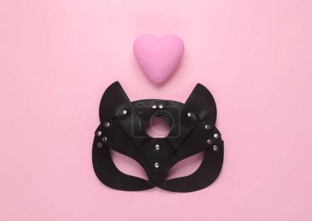 Téléchargez les photos : Masque de chat bdsm en cuir et coeur sur fond rose. Jeu de rôle sexuel. Concept d'amour. Vue de dessus. Pose plate - en image libre de droit