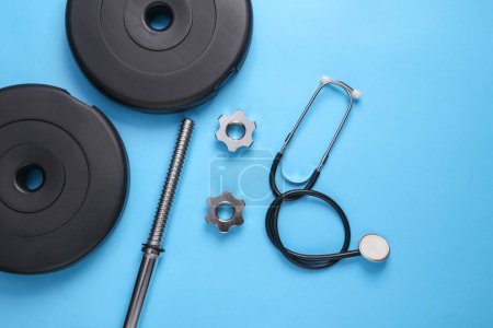 Foto de Concepto de salud y estado físico. Barbell con estetoscopio sobre fondo azul. Vista superior - Imagen libre de derechos