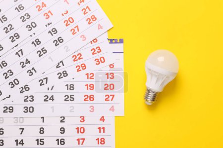 Kalender mit LED-Glühbirne auf gelbem Hintergrund. Ansicht von oben
