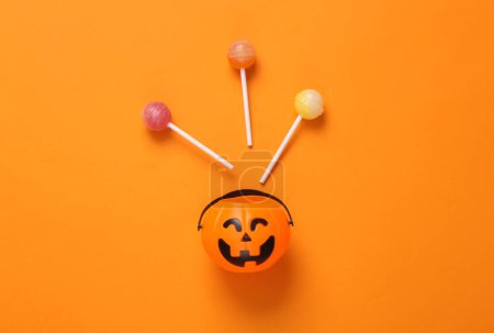 Foto de Cubo de linterna jack Halloween con piruletas sobre fondo naranja. Truco o trato, concepto de Halloween - Imagen libre de derechos