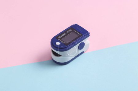 Foto de Oxímetro de pulso de dispositivo médico electrónico sobre fondo pastel azul-rosa. Medir la saturación de hemoglobina con oxígeno en la sangre capilar arterial. - Imagen libre de derechos