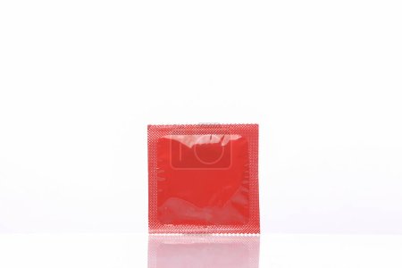 Rote Kondompackung isoliert auf weißem Hintergrund mit Reflexion