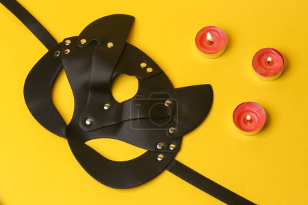 Téléchargez les photos : BDSM cat mask with flaming candles on a yellow background. Romantic, love concept - en image libre de droit