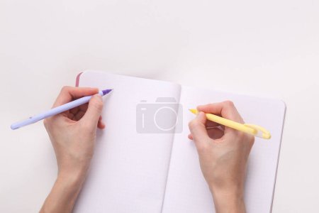 Photo for Two female hands (right and left) hand writes in an empty notebook on a gray background. Embidexter - Royalty Free Image