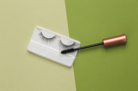Photo for Aesthetic still life false eyelashes with mascara brush on green background. Top view - Royalty Free Image