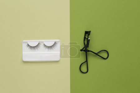 Téléchargez les photos : Aesthetic beauty layout with false eyelashes and Eyelash Curlers on a green background. Top view - en image libre de droit