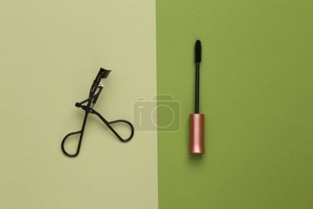 Téléchargez les photos : Aesthetic beauty layout with mascara brush and Eyelash Curlers on a green background. Top view - en image libre de droit