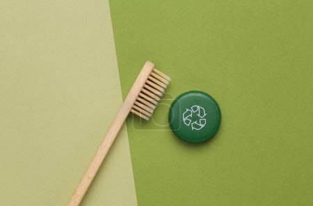 Foto de Tapa de botella de plástico con símbolo de reciclaje circular y cepillo de dientes de madera ecológico sobre fondo verde. Concepto de reciclaje redondo - Imagen libre de derechos