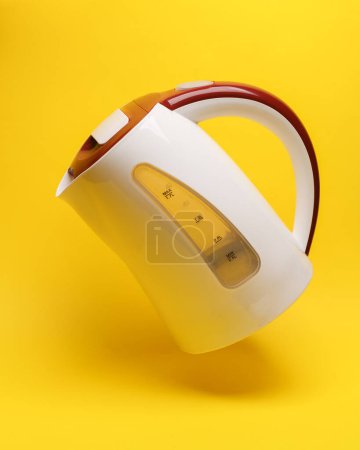 Téléchargez les photos : Bouilloire électrique lévite sur fond jaune avec ombre - en image libre de droit