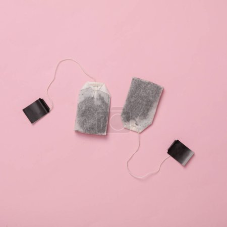 Two tea bags on a pink background. Top view