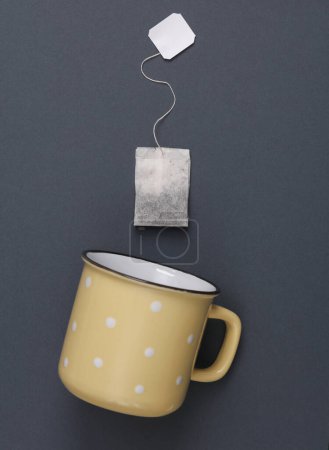 Cup with tea bag on gray background. Top view
