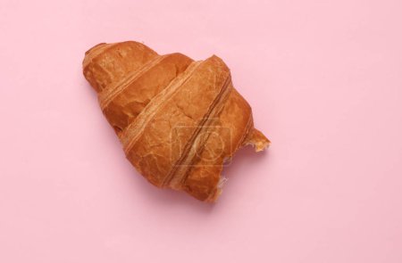 Photo for Appetizing bitten croissant on a pink background - Royalty Free Image