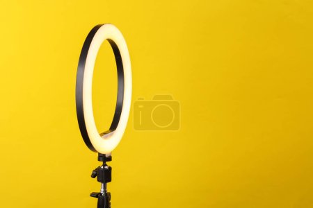 Foto de Lámpara de anillo led en trípode, fondo amarillo - Imagen libre de derechos