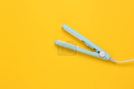 Photo for Mini hair straightener on yellow background. Top view - Royalty Free Image