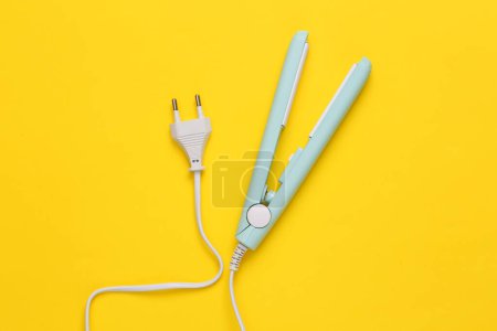 Photo for Mini hair straightener with cable on yellow background. Top view - Royalty Free Image
