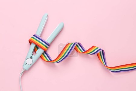 Photo for Hair straightener wrapped with lgbt rainbow ribbon on pink background - Royalty Free Image