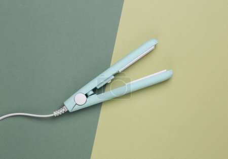 Photo for Mini hair straightener on green background. Top view - Royalty Free Image