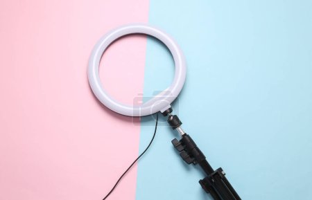 Led ring lamp with tripod on pink blue background. Gear for blogging and vlogging. Top view