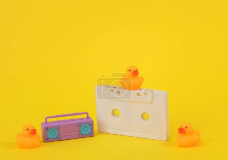 Foto de Patos de goma con cassette de audio y reproductor de audio boombox sobre fondo amarillo. Concepto musical - Imagen libre de derechos