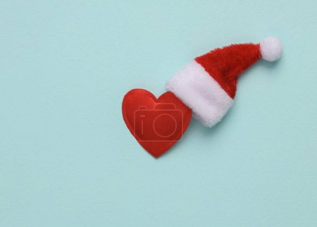 Coeur avec chapeau de Père Noël sur fond bleu. Concept de Noël