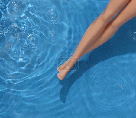 Muñeca patas en agua azul con sombras. Descanso. Vista superior