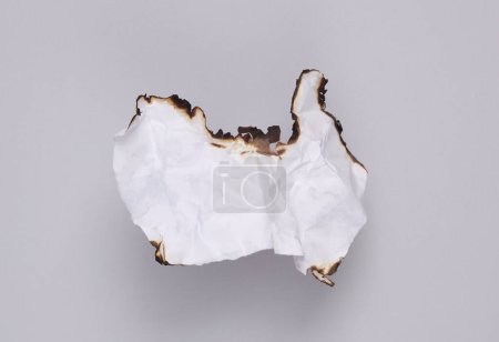 Photo for White crumpled sheet of paper charred on a gray background - Royalty Free Image