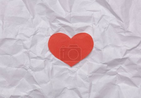 Red paper cut heart on crumpled paper. Love concept
