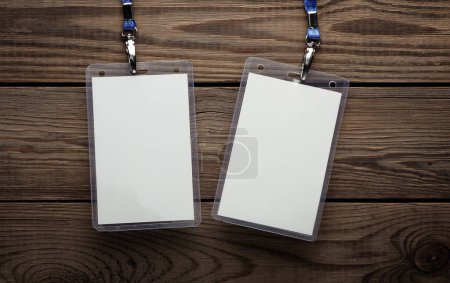 White ID card badges with belt on wooden table. Mockup for design template. Top view