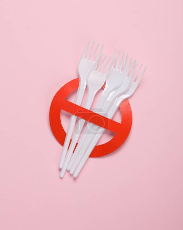 Foto de Tenedores de plástico con señal de prohibición roja sobre fondo rosa. Libre de plástico, detener la contaminación, concepto ecológico. Vista superior. Puesta plana - Imagen libre de derechos