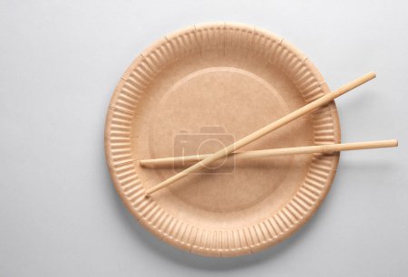 Foto de Placa de cartón artesanal ecológico con palillos chinos sobre un fondo gris. Vista superior - Imagen libre de derechos