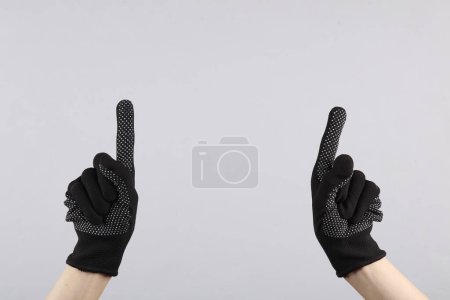 Foto de Las manos femeninas en guantes de tela de trabajo muestra los dedos en el espacio para el texto, sobre fondo gris - Imagen libre de derechos