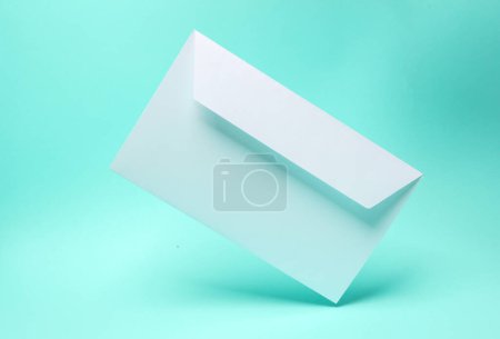 Téléchargez les photos : Enveloppe blanche lévitant sur fond bleu - en image libre de droit