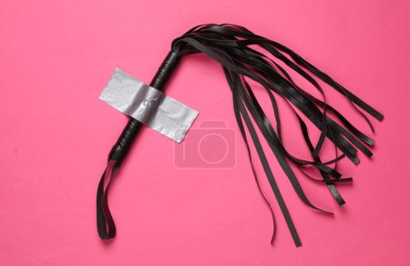 Photo for Leather sex shop whip fixed with adhesive tape on a pink background. - Royalty Free Image