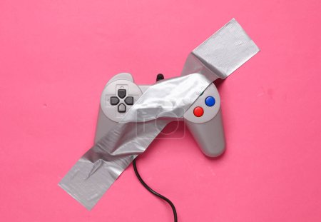 Photo for Retro gamepad fixed with adhesive tape on a pink background. Conceptual pop, video game - Royalty Free Image