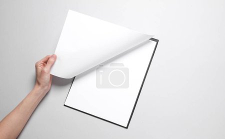 Photo for Female hand opens white blank clipboard page on gray background - Royalty Free Image