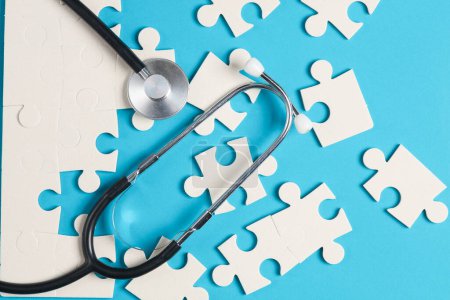 Photo for Jigsaw puzzle pieces and stethoscope on blue background. - Royalty Free Image