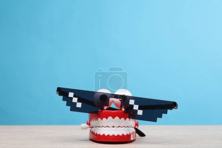 Photo for Joke jaw with pixel sunglasses on blue background - Royalty Free Image