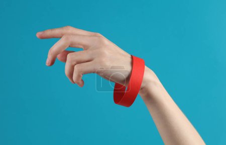 Photo for Female hand with a yellow paper bracelet on a blue background - Royalty Free Image
