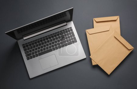 Photo for Laptop and Craft postal envelopes on dark gray background - Royalty Free Image