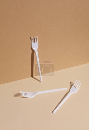 Foto de Tenedores de plástico blanco sobre fondo beige con sombra. Diseño creativo - Imagen libre de derechos