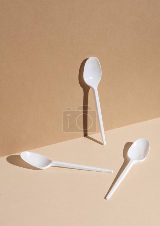Foto de Cucharas de plástico blanco sobre fondo beige con sombra. Diseño creativo - Imagen libre de derechos