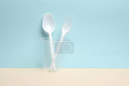 Foto de Tenedor de plástico y cuchara en vidrio sobre un fondo azul-amarillo. Diseño creativo - Imagen libre de derechos