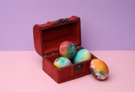 Chest with colored eggs on a pastel background. Conceptual Easter photo