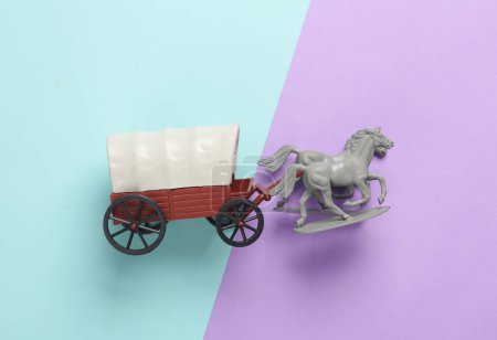 Toy cart with horses on a pastel background. Wild West