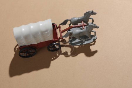 Toy cart with horses on a beige background. Wild West