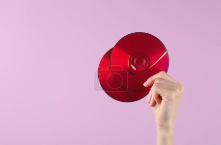 Photo for Hand holding cd disks on purple background - Royalty Free Image